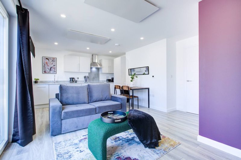 Modern studio apartment with blue sofa, kitchenette, and open-plan living area