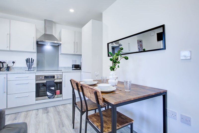 Modern kitchen with white cabinets, dining table, chairs and open shelving with potted plant