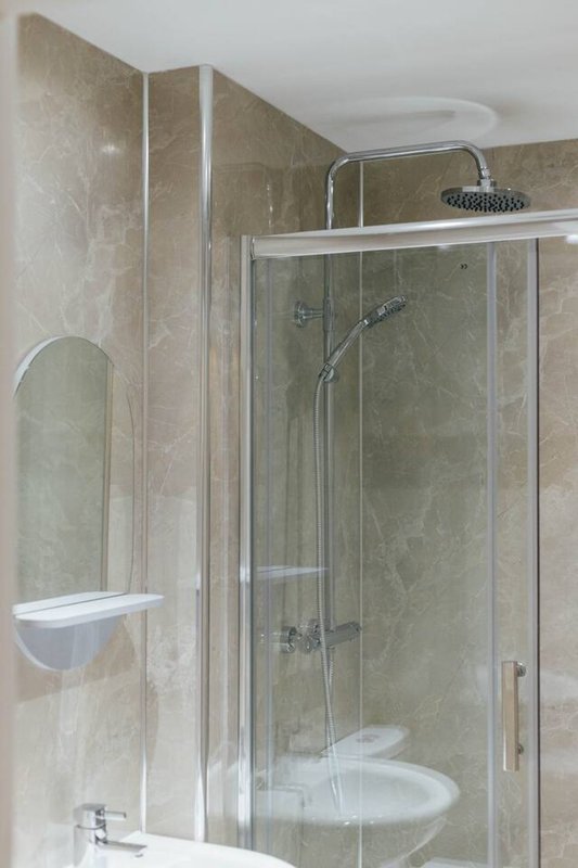 Modern bathroom with walk-in shower enclosure, rainfall showerhead and circular mirror