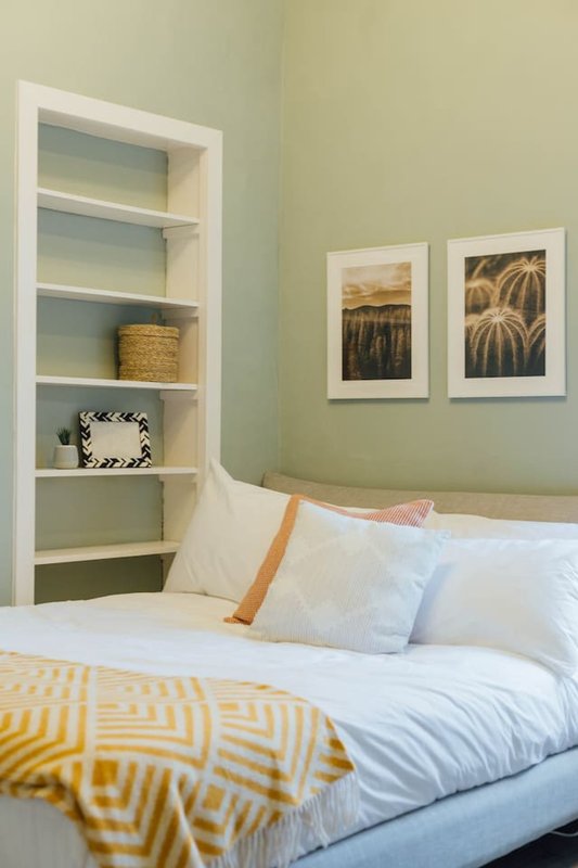 Bedroom with double bed, built-in shelving, wall art, and yellow geometric bedding