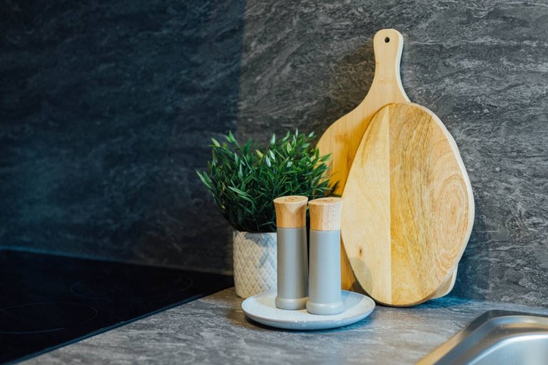 Kitchen counter with wooden cutting board, potted plant, and salt and pepper shakers