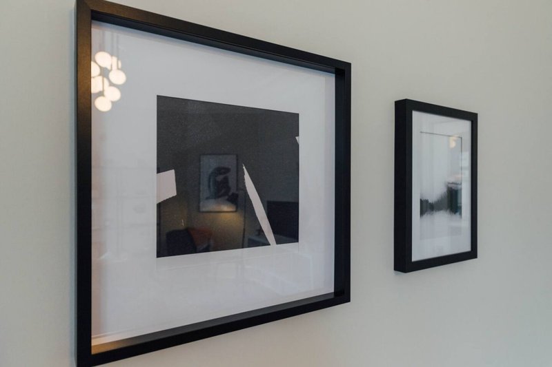 Wall-mounted framed artwork and photographs displayed on light gray wall