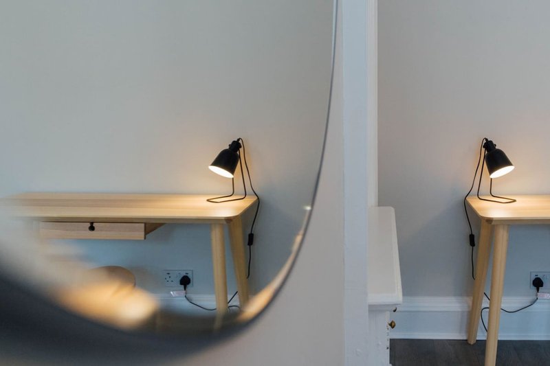 Two wooden desks with black task lamps and white walls, minimalist workspace setup