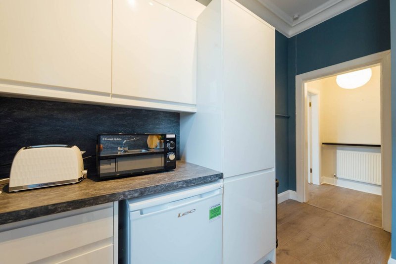 Modern kitchen with white cabinetry, black countertop, toaster, microwave and dishwasher