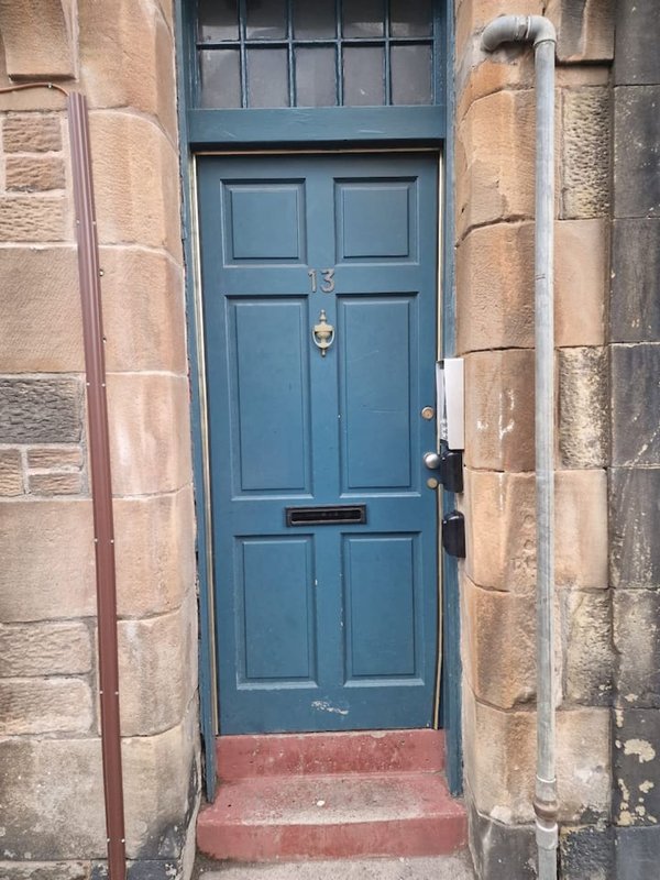 Blue front door with fanlight and red stone steps, flanked by stone pillars