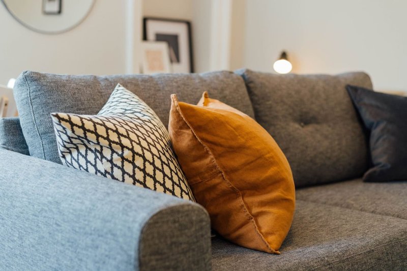 Gray upholstered sofa with patterned and leather cushions in living room