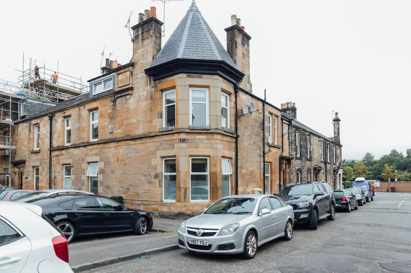 Stone Victorian corner building with turret, parked cars on street frontage