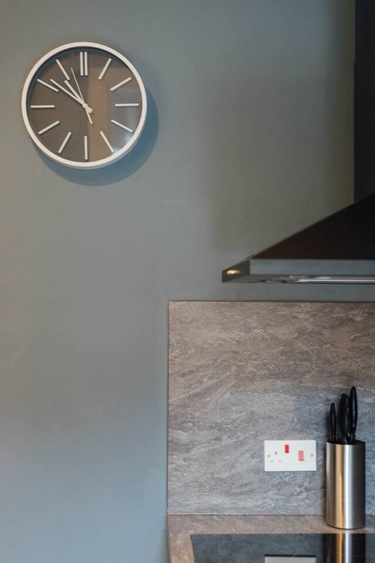 Modern kitchen corner with wall clock, knife block, and concrete backsplash