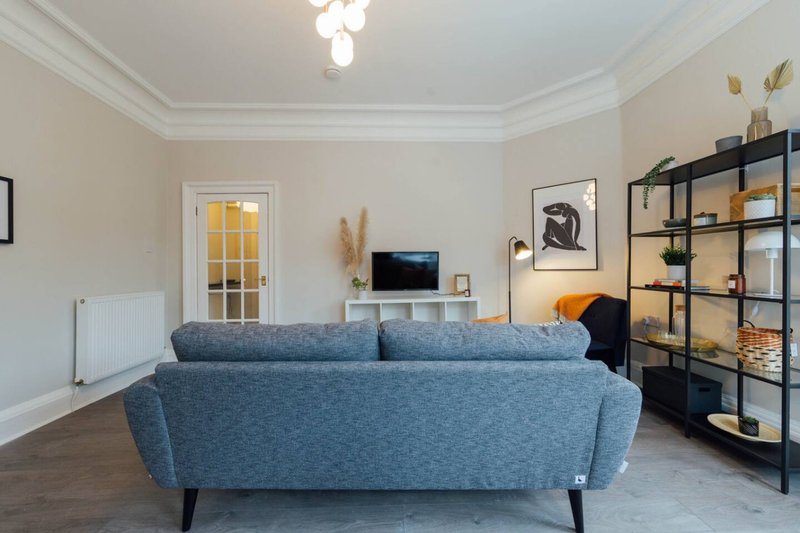 Modern living room with blue sofa, shelving unit, TV stand and wooden flooring