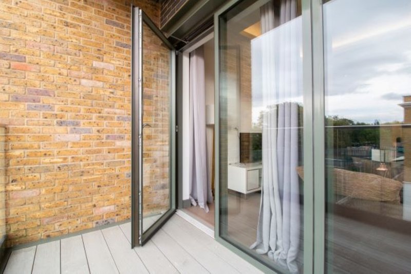 Modern patio area with brick wall, large glass sliding doors and white wooden decking