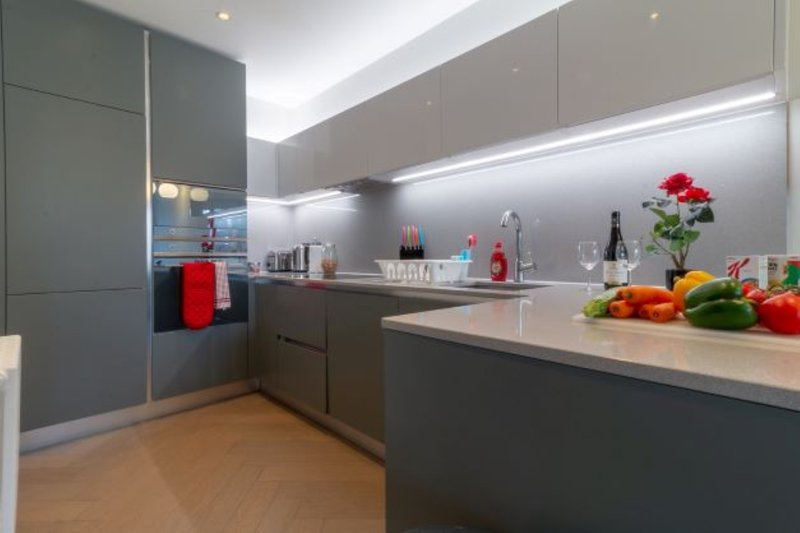 Modern grey kitchen with island counter, integrated appliances, fresh flowers and produce