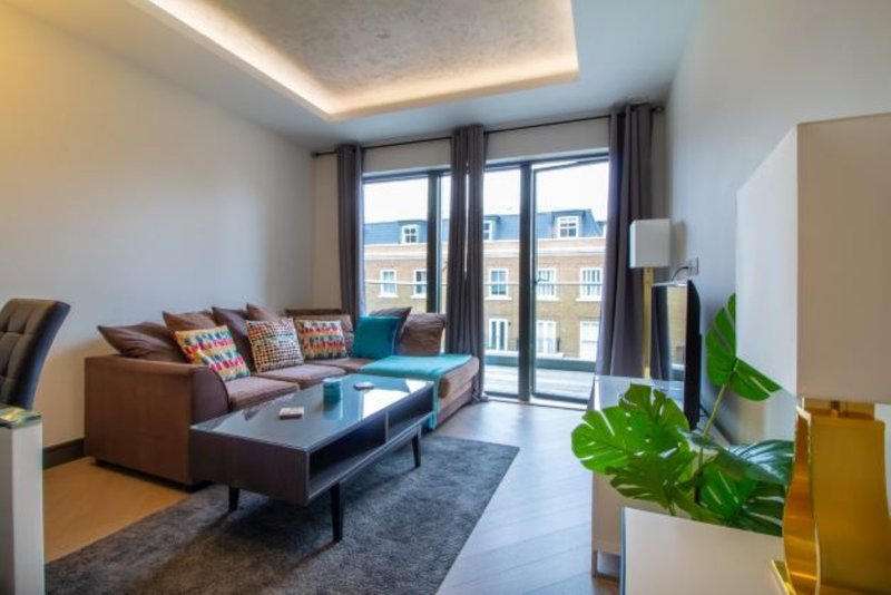 Modern living room with brown sofa, blue accent chair, glass coffee table and balcony doors overlooking city