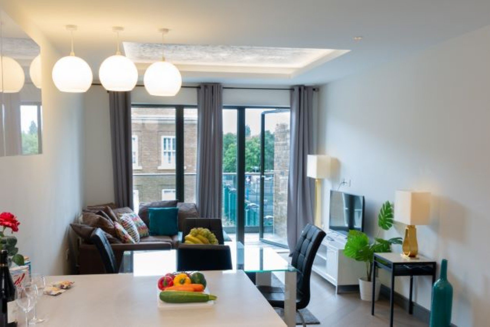 Modern living room with dining table, leather sofa, pendant lights and glass balcony doors