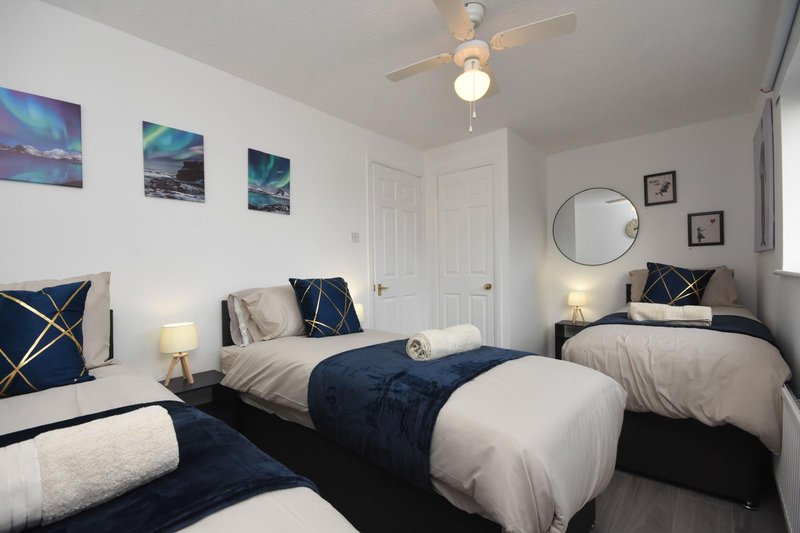 Bright bedroom with two single beds, navy bedding, framed artwork and circular mirror