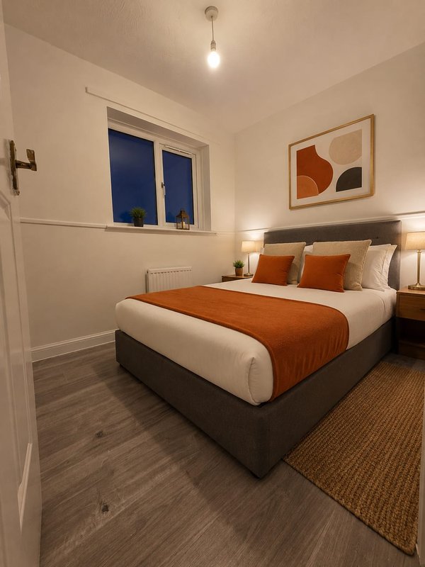 Modern bedroom with double bed, orange bedding, bedside lamps, and framed wall art