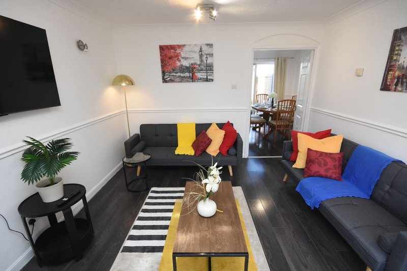 Spacious living room with dark sofas, colorful cushions, wooden coffee table and yellow striped rug