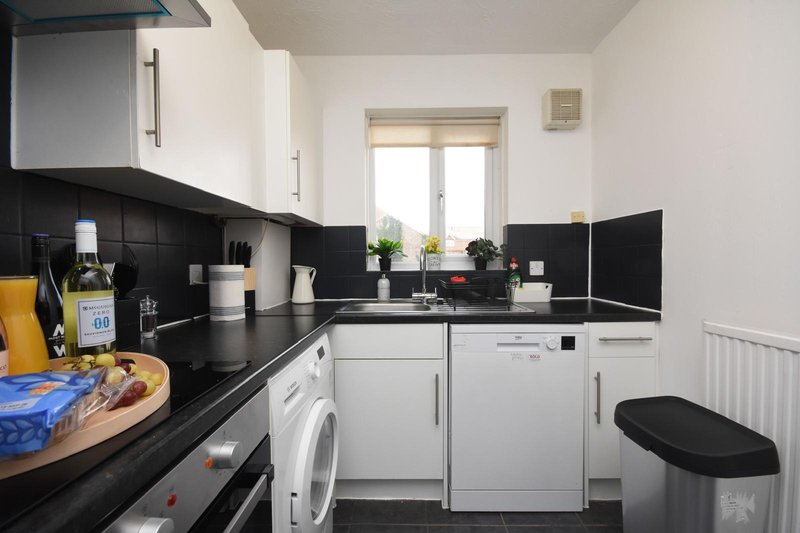 Modern kitchen with white cabinets, black countertops, appliances and window