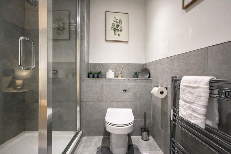 Ensuite Modern bathroom with toilet, walk-in shower, heated towel rail and grey tile walls