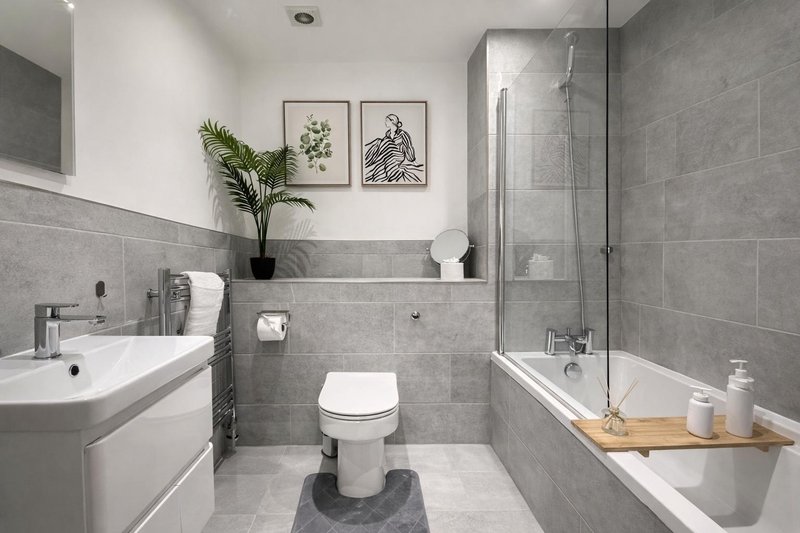 Main Guest Modern bathroom with gray tile, white sink, toilet, bathtub and shower enclosure