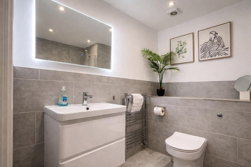 Modern bathroom with illuminated mirror, white vanity, towel rail and toilet