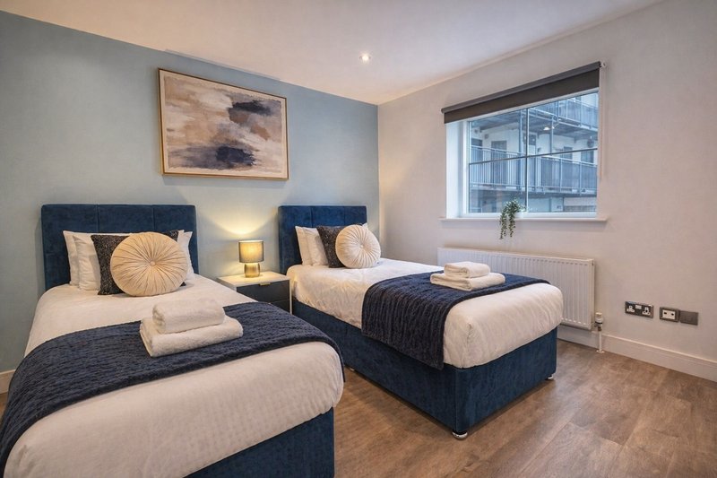 Master Bedroom can be made up as Twin bedroom with two dark blue beds, cream bedding, decorative cushions and framed artwork