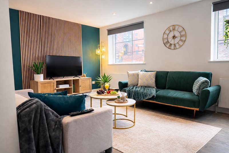 Modern living room with teal sofa, armchair, TV console and brass side table