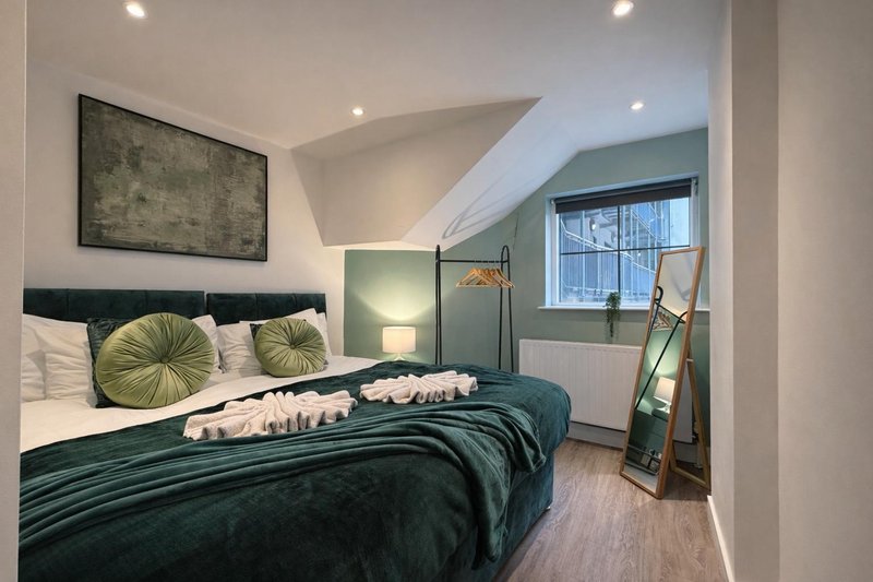 Modern bedroom with dark green super king zip link bed, geometric cushions, sloped ceiling and ladder mirror