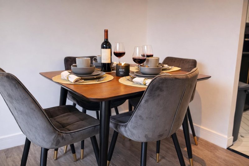 Dining table set for two with glasses, place settings and centerpiece candle.