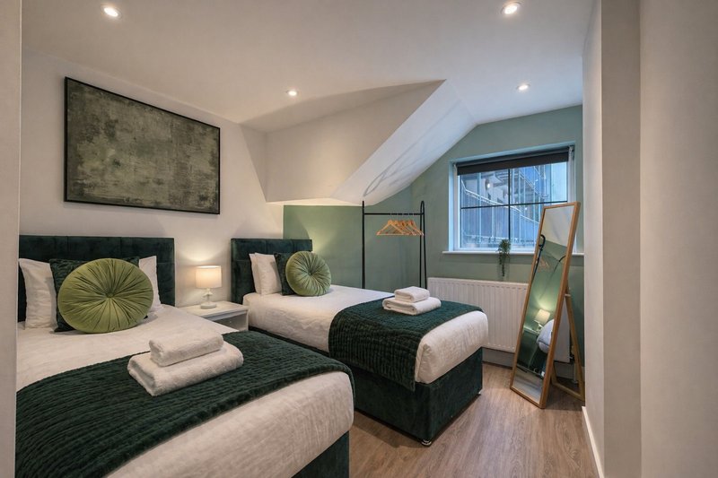Bedroom Two can be made up as a Twin bedroom with green and white bedding, matching cushions, wall art, and angled ceiling