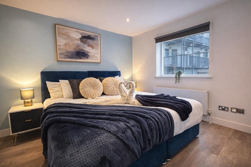 Modern bedroom with navy super king zip link bed, gold cushions, bedside lamp, and framed artwork