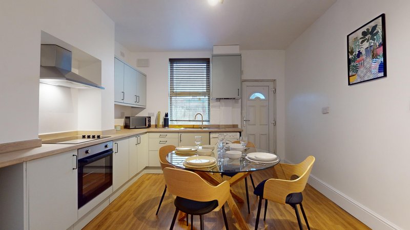 Modern kitchen-diner with cream cabinets, wooden flooring, dining table and yellow chairs