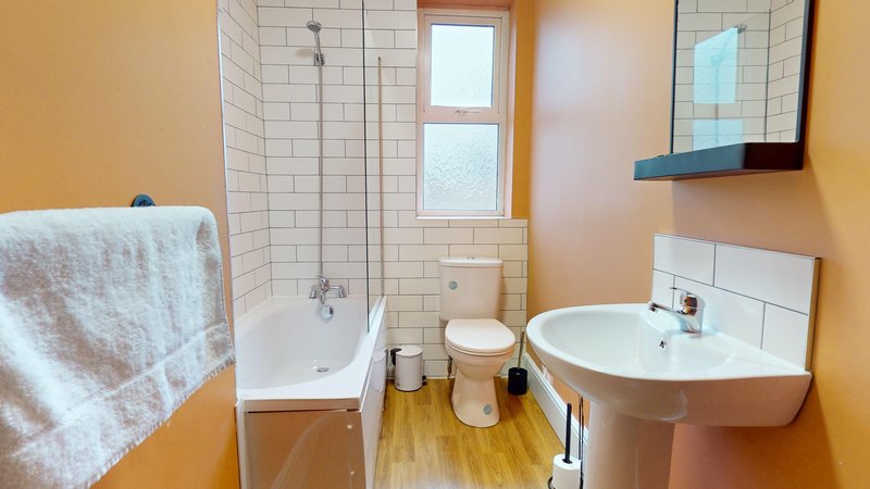 Bathroom with bathtub, pedestal sink, toilet, towel rail and mirror cabinet