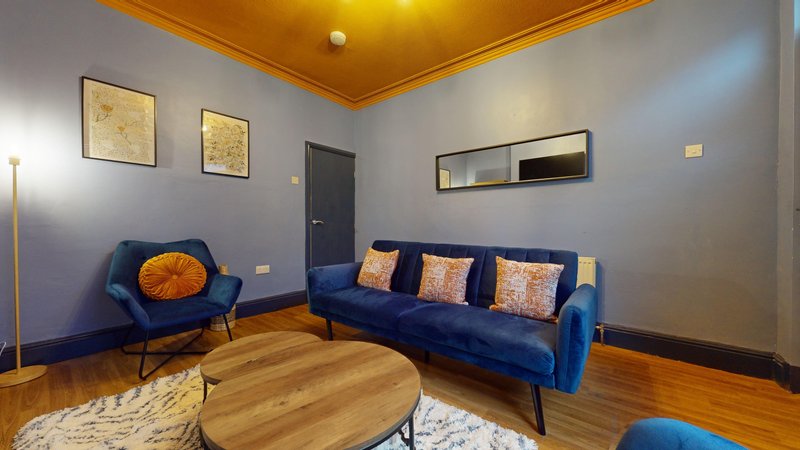 Modern living room with blue sofa, armchair, wooden floor and gold ceiling