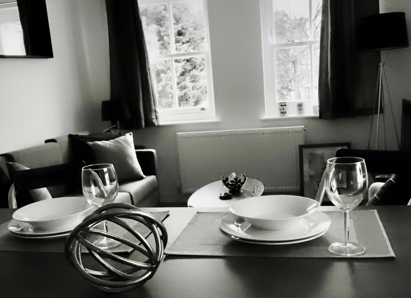 Modern dining table set with place settings, glasses, and decorative sphere, black and white interior