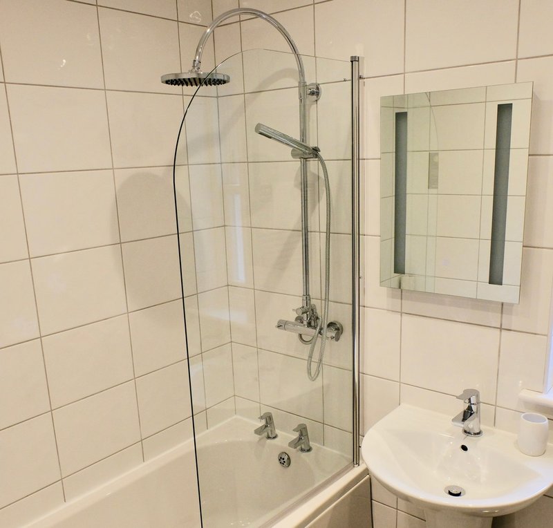 Modern bathroom with white subway tiles, glass shower enclosure, and circular wall-mounted mirror