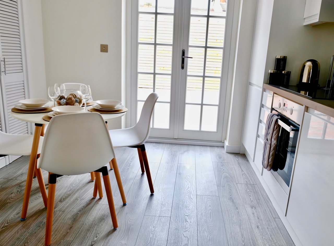 Modern kitchen-diner with dining table, chairs, white cabinetry and glass doors to garden