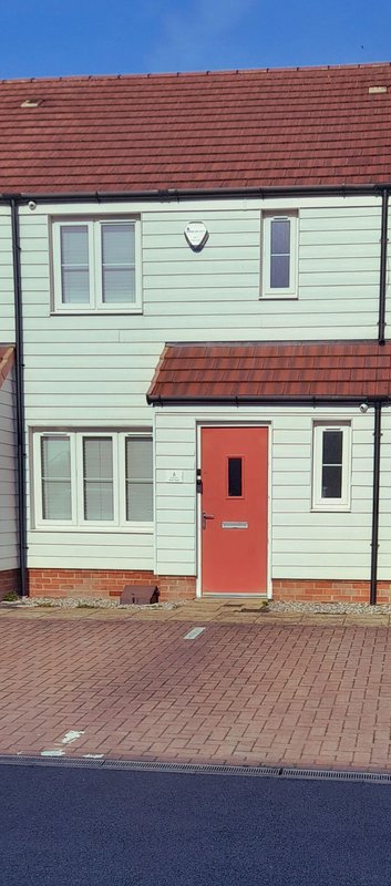 Two-storey semi-detached house with cream cladding, red roof, red door and brick driveway for 2 Cars or Vans.