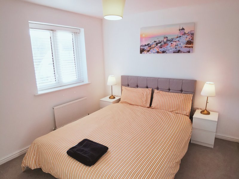 Master Bedroom (King bed) - Pink bedroom with double bed, striped bedding, two bedside lamps and wall art