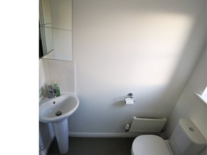 Downstairs toilet with pedestal sink, toilet, radiator and window