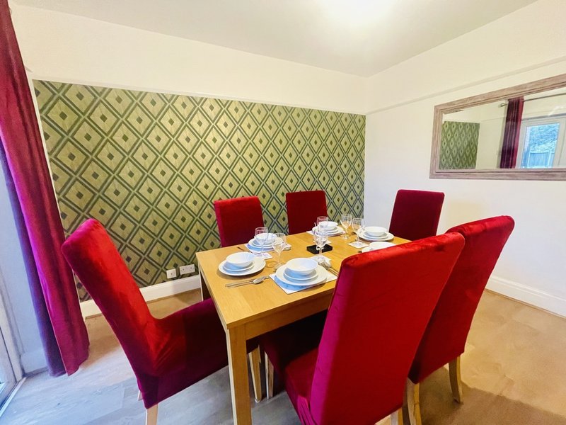 Dining room with wooden table, red velvet chairs, patterned wallpaper and window