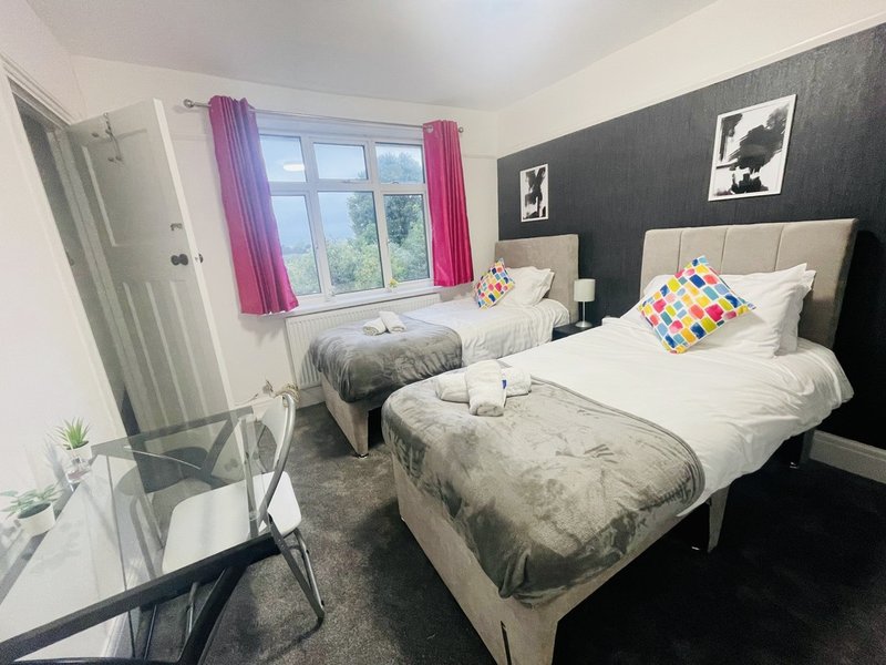 Twin bedroom with two single beds, dark accent wall, pink curtains and window view