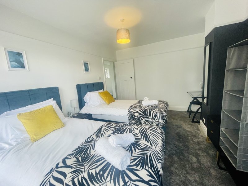 Bright bedroom with two single beds, blue headboards, yellow pillows, and zebra-patterned throw