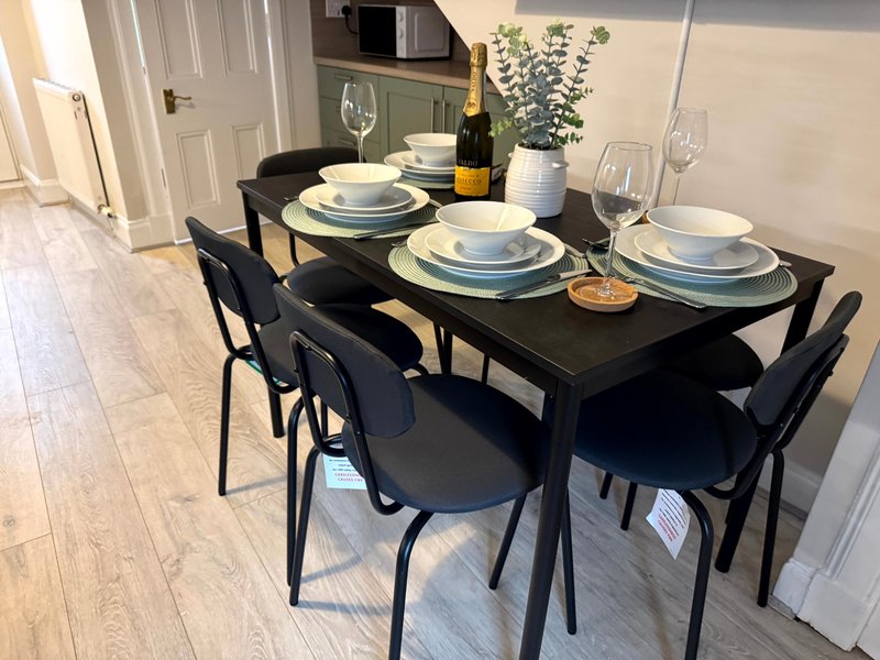 Dining table set for four with plates, glasses, and bottle of wine