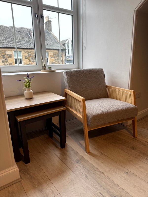 Modern sitting area with wooden desk, upholstered armchair and window overlooking street