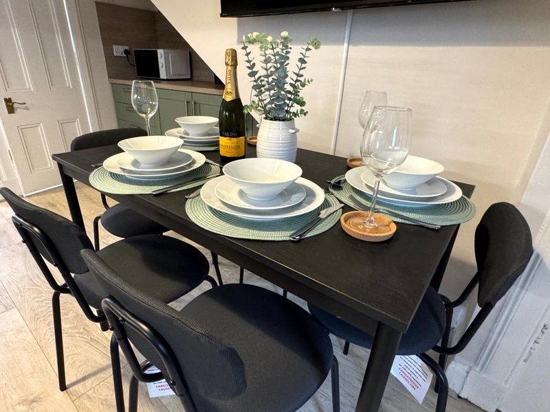 Dining table set with place settings, wine bottle, glasses and potted plant decoration