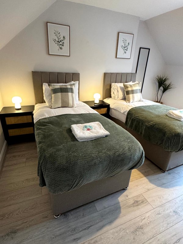 Twin bedroom with two beds, dark headboards, bedside lamps, and wall art