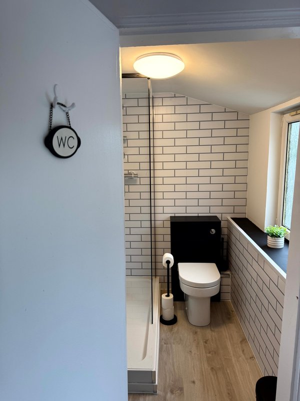 Modern bathroom with white subway tile walls, toilet, pedestal sink and floor lamp