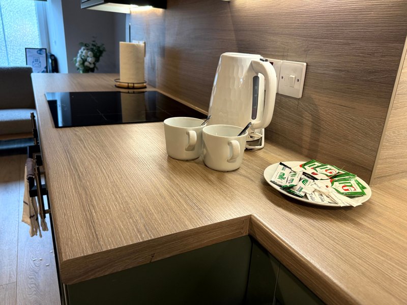 Modern kitchen counter with kettle, mugs, and decorative plate on wooden surface