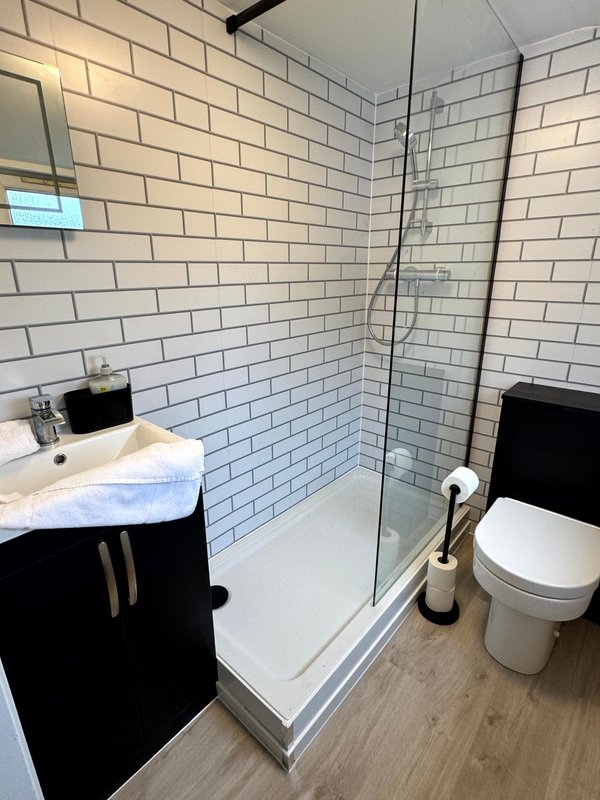 Modern bathroom with white subway tiles, black vanity, walk-in shower and toilet