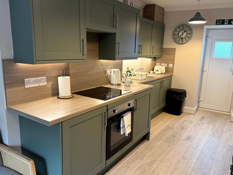 Modern kitchen with sage green cabinets, wooden countertops, built-in oven and integrated appliances